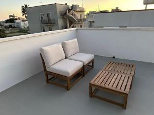 two chairs and a bench on a balcony at Dune House in Ginosa Marina