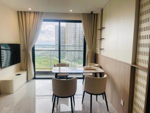 a dining room with a table and chairs and a large window at Đô thị Vinhomes Grand Park in Gò Công