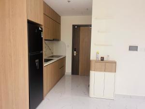 a kitchen with a black refrigerator and wooden cabinets at Đô thị Vinhomes Grand Park in Gò Công +1 photo
