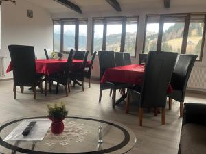 a dining room with red tables and chairs and windows at Casa Dani&Moni in Moieciu de Sus