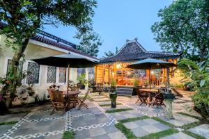 a patio with tables and umbrellas in front of a house at HOME 88 Feels Like Home in Sleman