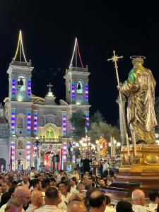 a crowd of people in front of a building with a statue at Apartment in Żebbuġ Malta in Ħal Muxi