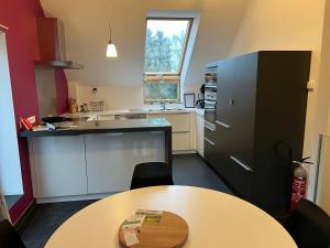 a kitchen with a table and a black refrigerator at Gîte Fenêtres sur cour - Genappe in Genappe