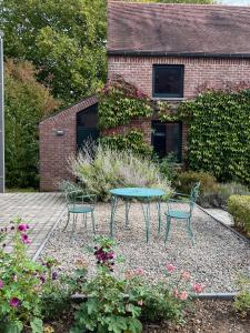 a patio with two chairs and a table in a garden at Gîte Fenêtres sur cour - Genappe in Genappe +6 photos