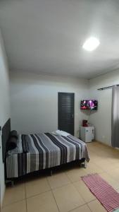 a bedroom with a bed and a flat screen tv at Pousada Central in Montes Claros