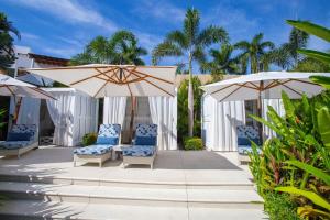 a patio with umbrellas and chairs and palm trees at Elegance - Jungle meet with private pool heated in Bucerías