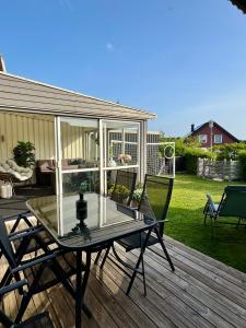 a glass table on a wooden deck with chairs at Hus, barnvänligt, nära strand in Halmstad