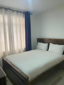 a bed with a wooden headboard and white pillows at Residence Next Door Gz in Kiambu +13 photos