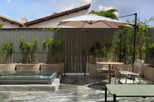a patio with a table and chairs and an umbrella at Íz Hotel Conceito in Goiânia
