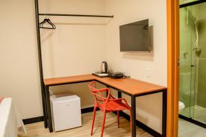 a room with a desk with a chair and a television at Viamar Home in Natal