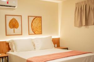 a bedroom with a bed and two pictures on the wall at Viamar Home in Natal