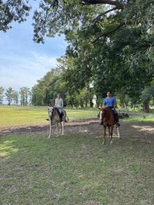 two people riding on horses in a field at Casa del monte in Carmen de Areco
