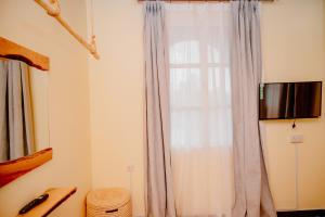a room with a curtain and a window at Roots and Waves in Zanzibar City +28 photos