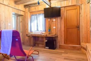 a room with a red chair and a desk and a television at GIAMI affittacamere & SPA in Santa Giustina