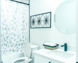 ein weißes Badezimmer mit Toilette und Duschvorhang in der Unterkunft Ebenz Apartment in Calgary + 38 Fotos