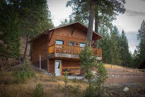 a large wooden cabin in the woods with a balcony at Radium Cabins Centrally located in Radium Hot Springs BC in Radium Hot Springs