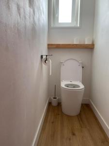 a white bathroom with a toilet with a window at Tall Ar Groas in Plogoff
