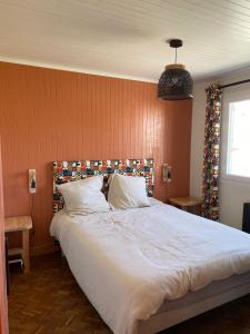 a bedroom with a large white bed with orange walls at Tall Ar Groas in Plogoff