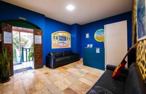 a living room with a black leather couch and blue walls at Onça da Praia Hostel in Vitória