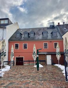 a large orange and white building with a brick driveway at Macabu Apartment Porto in Plauen