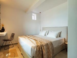 a bedroom with a white bed and a chair at Trinitas Mare Psarou Beach in Psarou