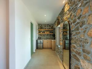 a stone wall in the kitchen of a house at Trinitas Mare Psarou Beach in Psarou +13 photos