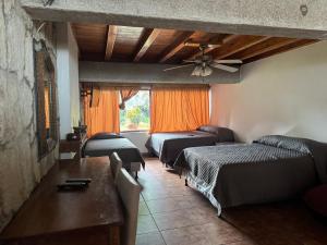 a bedroom with three beds and a ceiling fan at Bungalós brunos in Panajachel