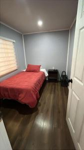 a bedroom with a bed with a red blanket at Cabaña en Ancud in Ancud +2 photos