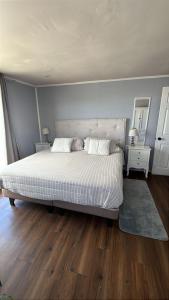 a bedroom with a large white bed and wooden floors at Cabaña en Ancud in Ancud