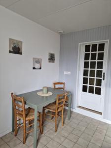 a dining room with a table and chairs and a door at L'Instant Bourguignon in Montceau-les-Mines
