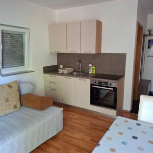 a kitchen with white cabinets and a couch in a room at Apartments Oliva - Maslina in Bilice