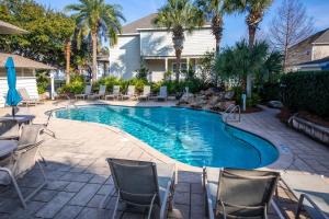 a swimming pool with chairs and tables and palm trees at Hello Sunshine in Santa Rosa Beach