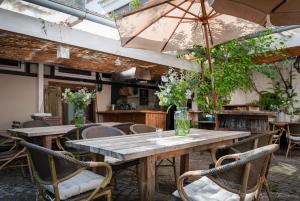 a large wooden table with chairs and an umbrella at Kaffee&Kissen - Das Boutique Hotel am Rhein in Oestrich-Winkel
