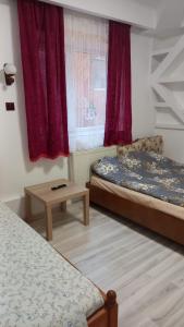 a bedroom with two beds and a table and a window at CASA CU LAVANDĂ in Vatra Dornei