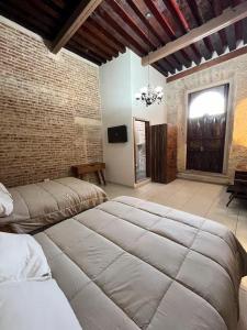 a bedroom with two beds and a brick wall at Casa Alzate in Morelia