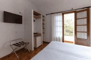 ein Schlafzimmer mit einem Bett und einem Fernseher an der Wand in der Unterkunft VOA Hotel União in Caxambu
