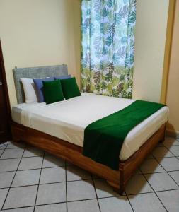 a bed in a room with a green blanket on it at Hotel Los Rivera in David
