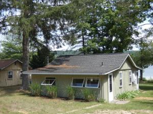 a small house with a tree in front of it at Sandy Bottom Cottage on Intermediate Lake in Bellaire