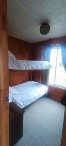a bedroom with two bunk beds and a window at CABAÑA HUALAIHUE AUSTRAL in Hornopiren