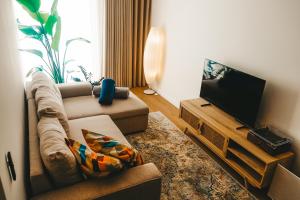 a living room with a couch and a flat screen tv at Slow Living Apúlia in Apúlia