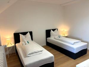 a bedroom with two beds with white sheets and lamps at Naturhotel Blaubach in Blaubach +49 photos
