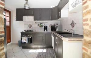 a kitchen with gray cabinets and a stove at Maison pour s’évader à la campagne in Trancault +2 photos