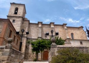 a large stone building with a tower and a door at Casa Rural La Vid in Cadalso de los Vidrios
