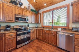 a kitchen with wooden cabinets and a large window at Firefly Cove by Railey Vacations in McHenry