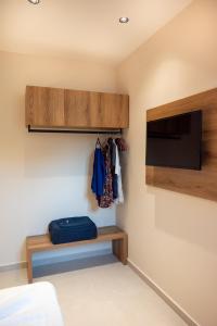 a bedroom with a tv and a shelf and a bed at Mystrali 1BD Modern Apt with Private Garden in Galatás +21 photos