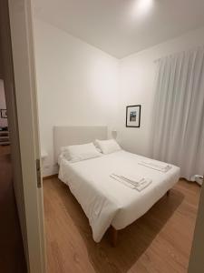 a white bed in a white bedroom with white curtains at PALAZZO MARCHETTI in Ancona