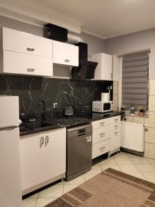 a kitchen with white cabinets and a sink at Villa Varzob lll in Warsaw