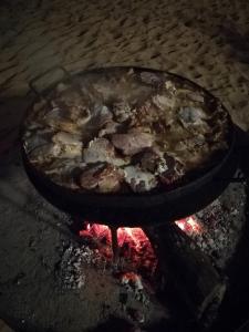 a pizza cooking in a pan on a fire at Cabaña DEK in Tigre