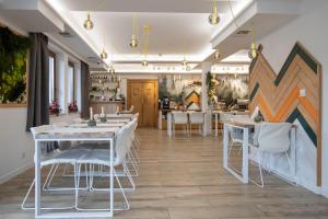 a dining room with white tables and white chairs at Novobilski przy Termie Bania i Kotelnicy - sauna, jacuzzi, restauracja, pokój zabaw, wypożyczalnia rowerów e-bike in Białka Tatrzańska