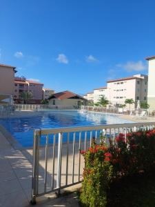 a swimming pool with a fence and some flowers at Residencial Clube Recanto dos Coqueiros in Aracaju